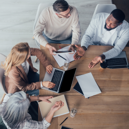 Photo of four employees sitting around a table talking.